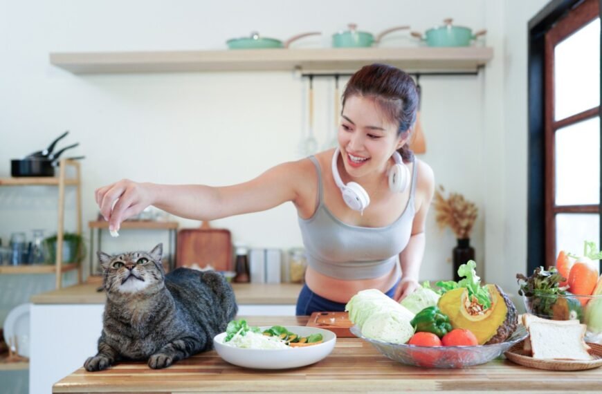 Young pet owner feeds cat from the table.